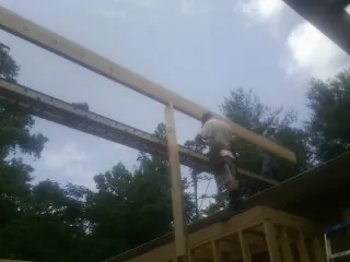 Carpenter setting a ridge beam over a new addition frame — Ice Dam Removal by Roofing Brothers in Saint Ignatius