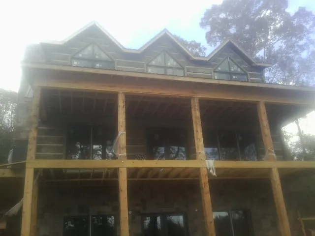 Dormers and porch framing on a large log home under construction — Roof Coating work by our crew in Saint Ignatius