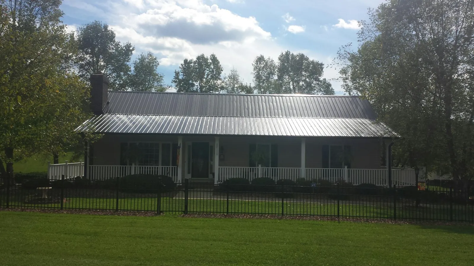 Gray metal roof on a brick ranch with a full width front porch — Gutter Guard Installation work by our crew in Saint Ignatius