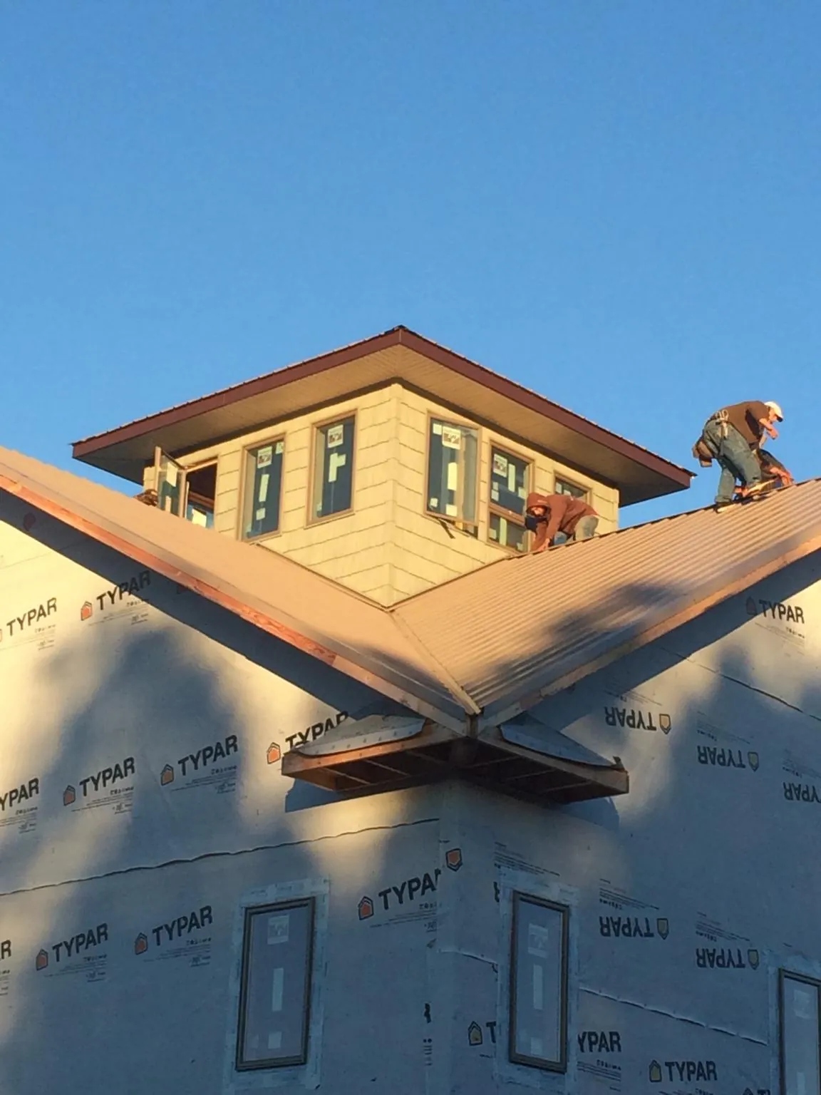 Roofers working around a rooftop cupola on a new metal roof at sunset — Roof Waterproofing in Saint Ignatius by Roofing Brothers